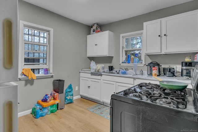 kitchen with a sink, plenty of natural light, light wood-style floors, and white cabinetry