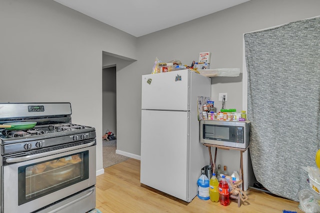 kitchen featuring stainless steel appliances, light wood-type flooring, and baseboards