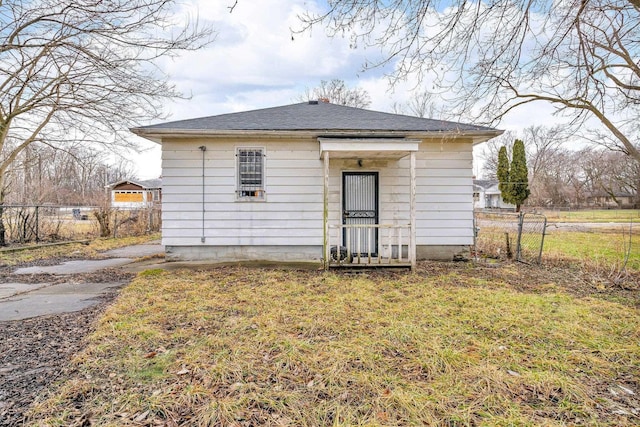 rear view of property with a yard, a shingled roof, and fence