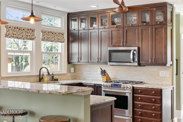 kitchen featuring pendant lighting, backsplash, appliances with stainless steel finishes, and a sink