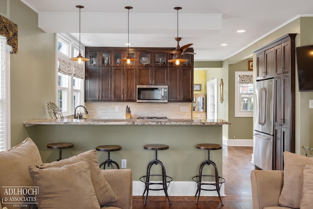 kitchen with crown molding, light stone counters, backsplash, and appliances with stainless steel finishes