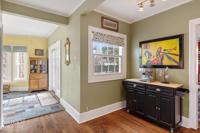 entrance foyer featuring wood finished floors, baseboards, and ornamental molding