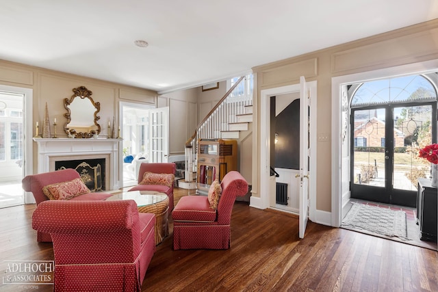 living room featuring wood finished floors, stairway, french doors, a fireplace, and a decorative wall