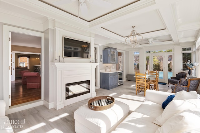 living room with beverage cooler, coffered ceiling, beam ceiling, ceiling fan with notable chandelier, and light wood-type flooring