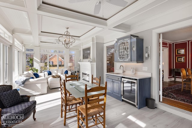 dining area with beverage cooler, coffered ceiling, beam ceiling, a glass covered fireplace, and crown molding