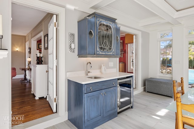 bar featuring light wood finished floors, beverage cooler, ornamental molding, beam ceiling, and a sink