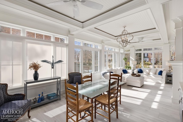 sunroom / solarium featuring beamed ceiling, plenty of natural light, ceiling fan with notable chandelier, and coffered ceiling