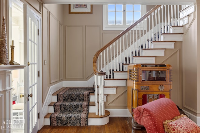 foyer entrance with a decorative wall, stairway, and wood finished floors