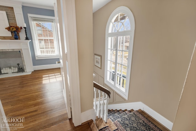 entrance foyer featuring stairway, a fireplace, baseboards, and wood finished floors