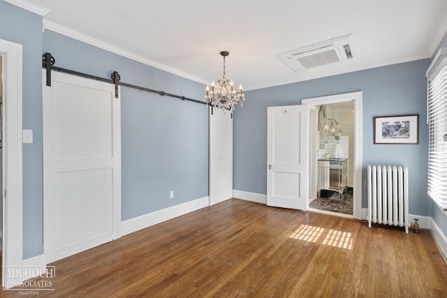 interior space featuring a barn door, wood finished floors, radiator heating unit, and ornamental molding