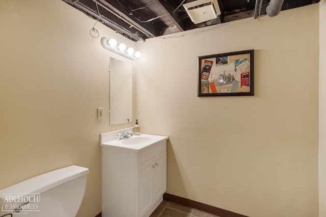 half bathroom featuring vanity, toilet, and baseboards