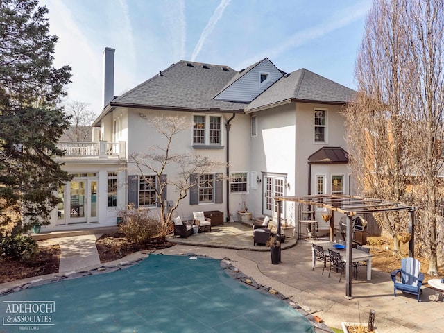 rear view of property featuring an outdoor living space, roof with shingles, french doors, a balcony, and a patio