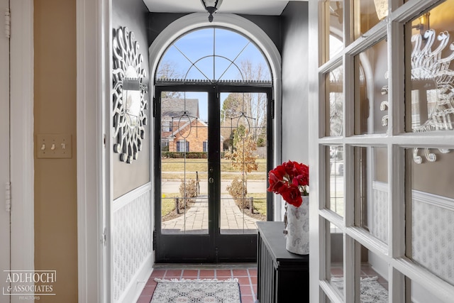 foyer entrance with tile patterned flooring and a wainscoted wall