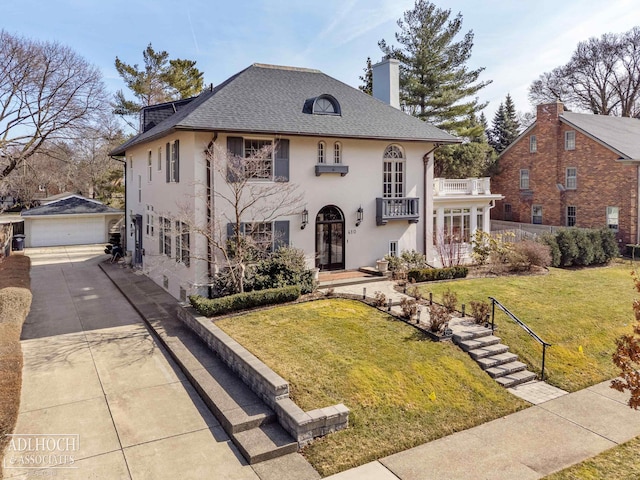 view of front of home featuring a detached garage, french doors, an outdoor structure, a front yard, and a balcony