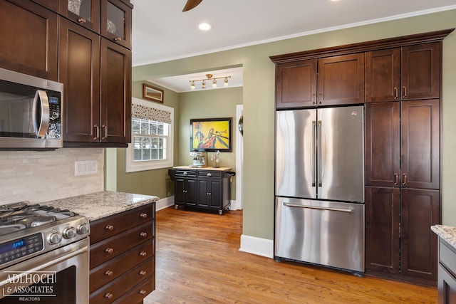 kitchen featuring light stone counters, light wood finished floors, ornamental molding, stainless steel appliances, and tasteful backsplash