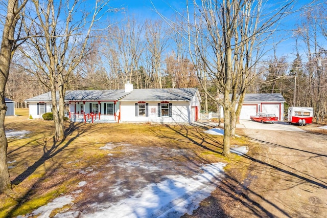 ranch-style house with covered porch, an outdoor structure, a front yard, a garage, and a chimney