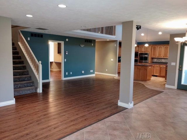 unfurnished living room with baseboards, recessed lighting, stairs, light wood-type flooring, and a chandelier