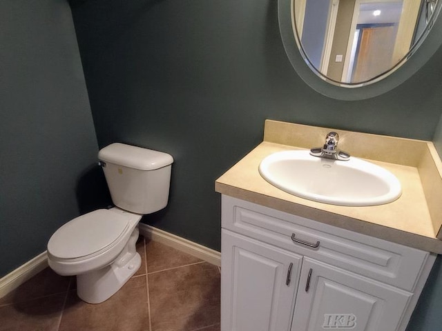 half bath with tile patterned flooring, toilet, vanity, and baseboards