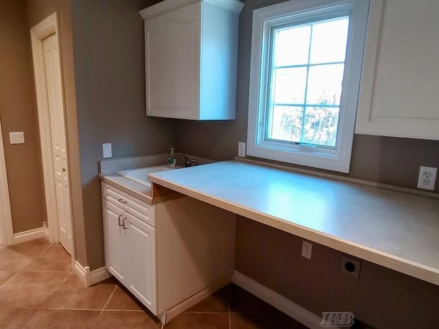 kitchen featuring a sink, white cabinets, light countertops, light tile patterned floors, and built in study area