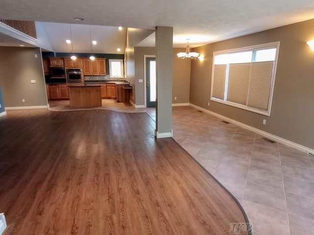 kitchen featuring a chandelier, open floor plan, a kitchen island, and baseboards