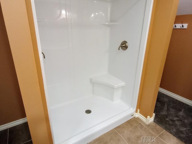 bathroom with tile patterned floors, baseboards, and a stall shower