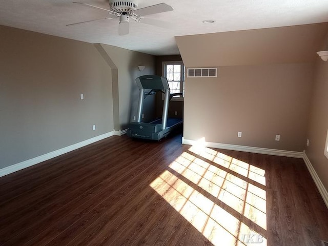 interior space with a ceiling fan, baseboards, visible vents, and dark wood-style flooring