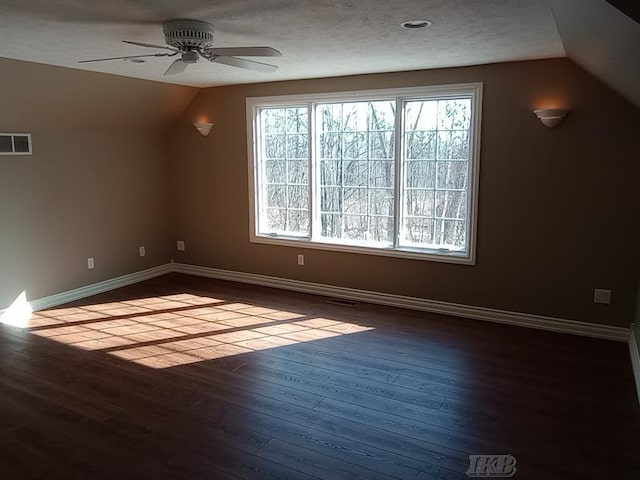 bonus room with dark wood finished floors, visible vents, baseboards, and lofted ceiling