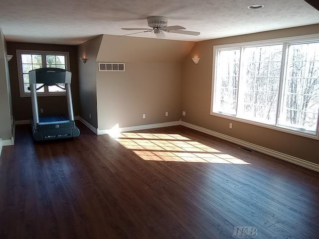 unfurnished living room with visible vents, a textured ceiling, baseboards, and dark wood-style flooring