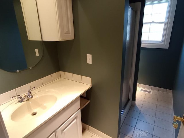 bathroom featuring vanity, tile patterned floors, baseboards, and a stall shower