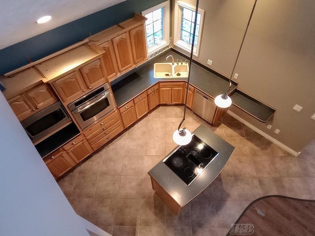 kitchen featuring light tile patterned floors, stainless steel appliances, dark countertops, and a sink