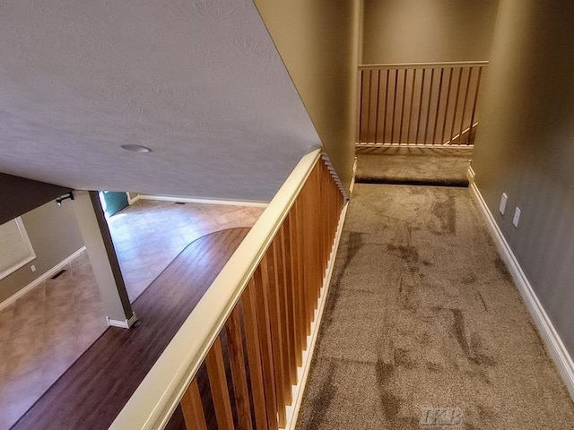 stairway with baseboards, carpet, and a textured ceiling