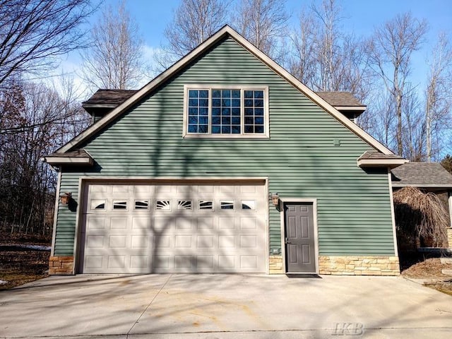 view of side of home with stone siding and driveway