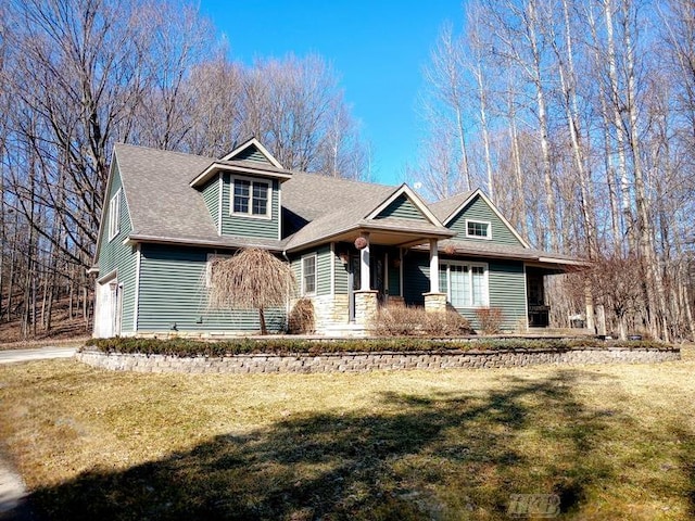 view of front of house with a front yard, an attached garage, and roof with shingles