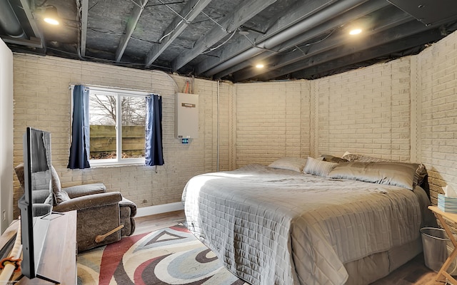 bedroom with brick wall and wood finished floors