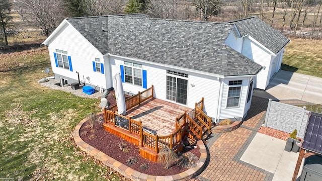 rear view of property with a patio area, a lawn, roof with shingles, and a wooden deck