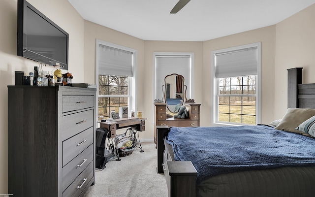 bedroom featuring light colored carpet, baseboards, and ceiling fan