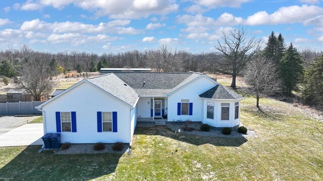 ranch-style home with a front lawn, fence, and a shingled roof