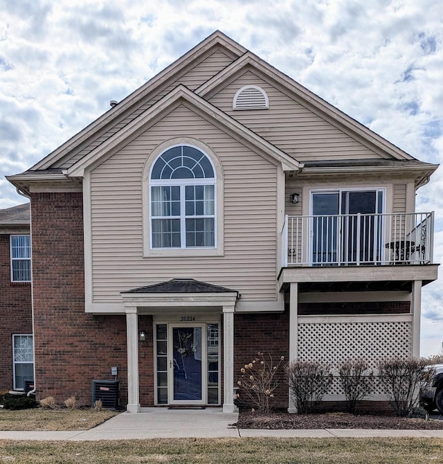 view of front facade with brick siding and a balcony