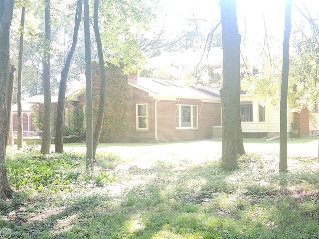 back of house featuring brick siding and a chimney