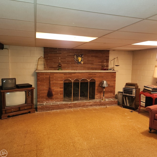 living area featuring tile patterned floors, a brick fireplace, and concrete block wall