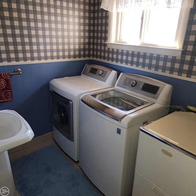 washroom with laundry area, washing machine and clothes dryer, wainscoting, and wallpapered walls