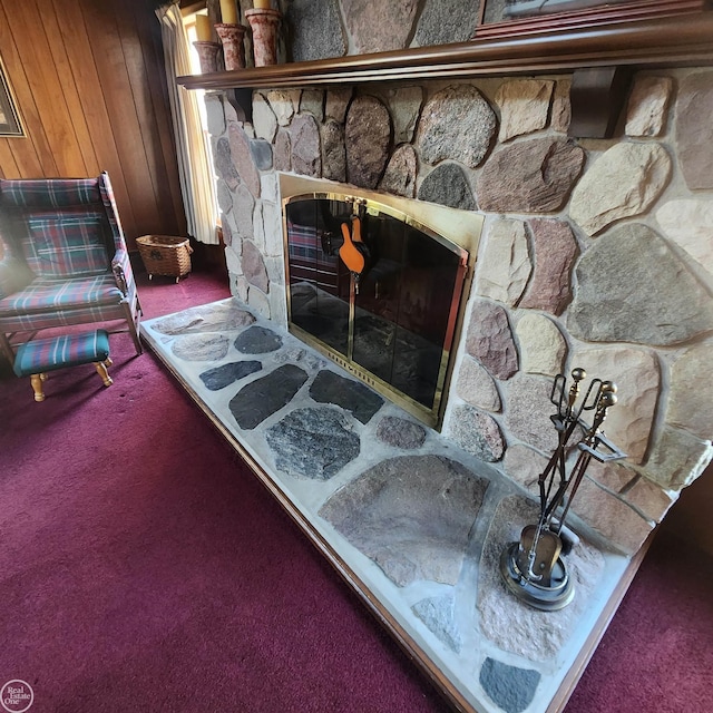 interior details featuring a stone fireplace, wooden walls, and carpet