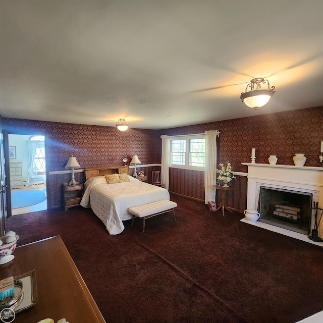 bedroom featuring a fireplace with flush hearth, carpet flooring, and wallpapered walls