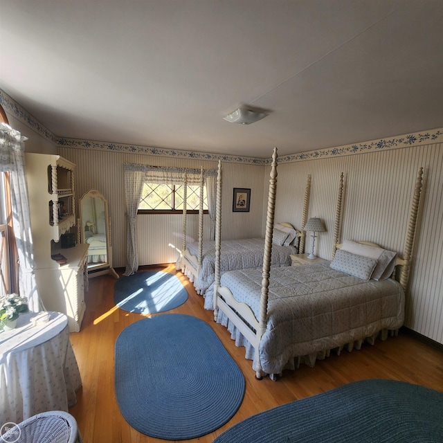 bedroom with wood finished floors and wallpapered walls