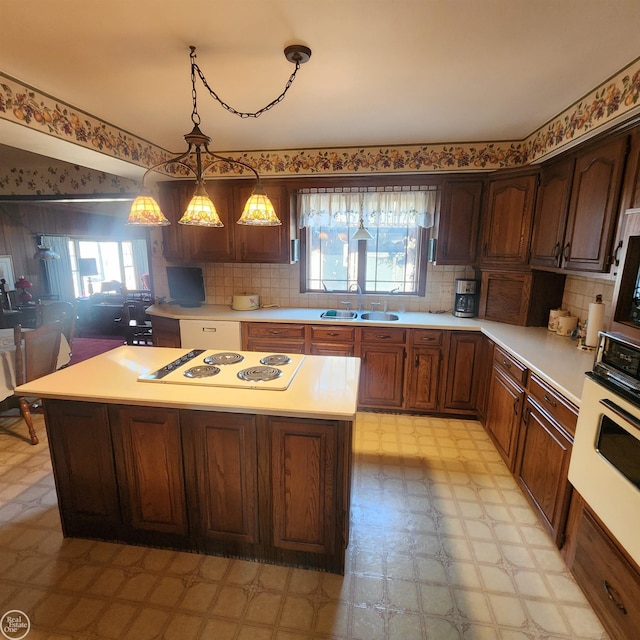 kitchen with a wealth of natural light, a sink, white appliances, light countertops, and light floors