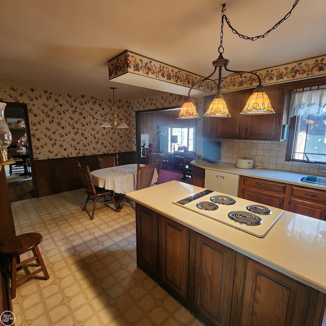 kitchen with wallpapered walls, a wainscoted wall, light floors, light countertops, and white appliances