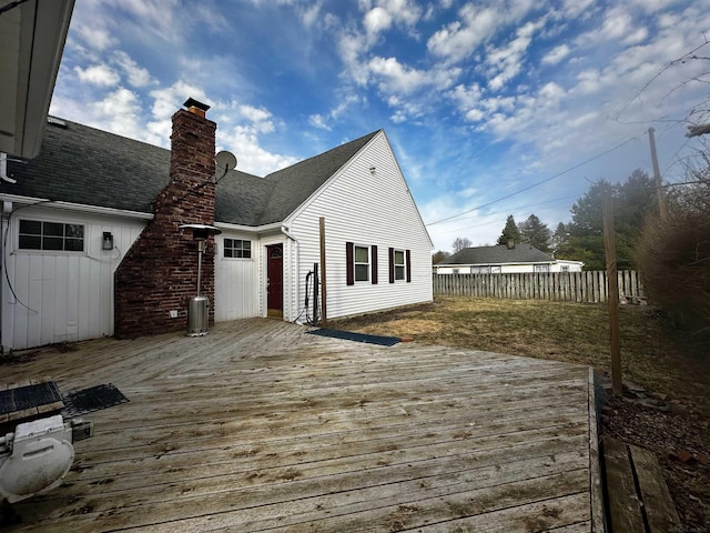 rear view of property with a shingled roof, fence, a chimney, and a wooden deck