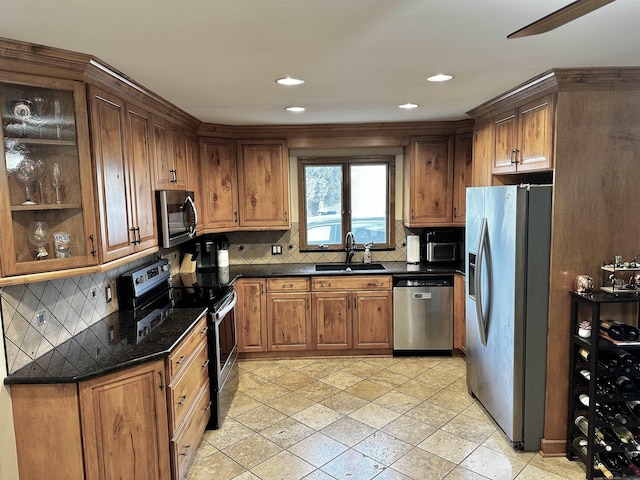 kitchen with a sink, backsplash, appliances with stainless steel finishes, and brown cabinetry