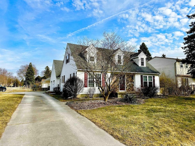 new england style home with concrete driveway and a front lawn