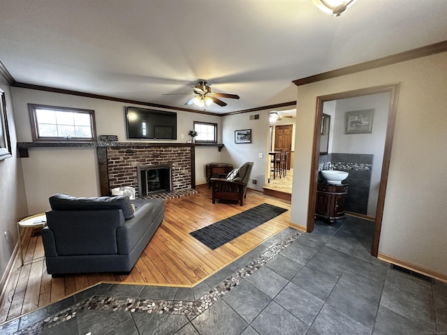 living area featuring a brick fireplace, a wealth of natural light, and ornamental molding